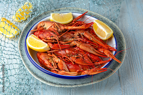 Boiled crayfish or lobster with aromatic herbs and lemon on a blue background. Mediterranean Kitchen. Sea mood menu.
