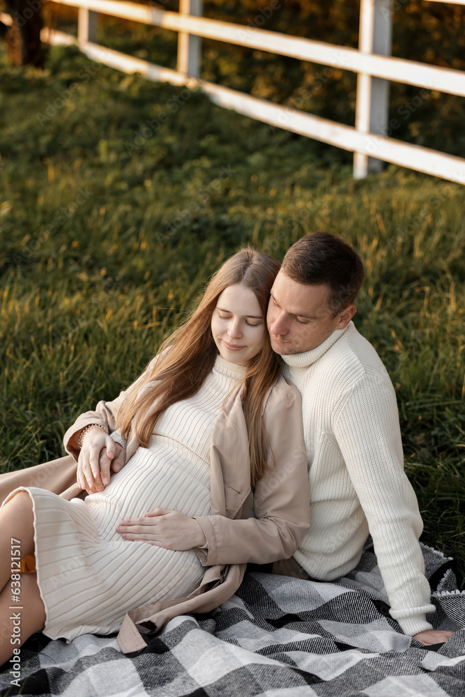 Mothers day. Stylish marriage pregnant couple waiting for baby. Man hugs and touches woman belly outdoors on plaid on grass. Family day. Pregnancy, parenthood, motherhood, love, family concept.