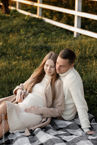 Mothers day. Stylish marriage pregnant couple waiting for baby. Man hugs and touches woman belly outdoors on plaid on grass. Family day. Pregnancy, parenthood, motherhood, love, family concept.