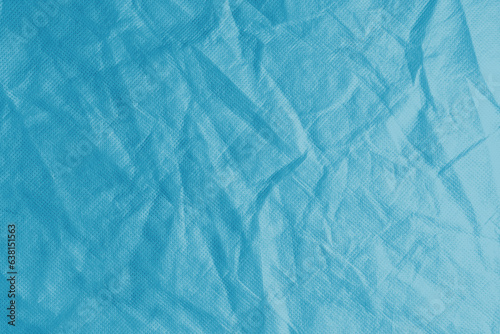 Wrinkled, crumpled blue fabric texture background. Wrinkled and creased abstract backdrop of spunbond textile, wallpaper with copy space, top view.