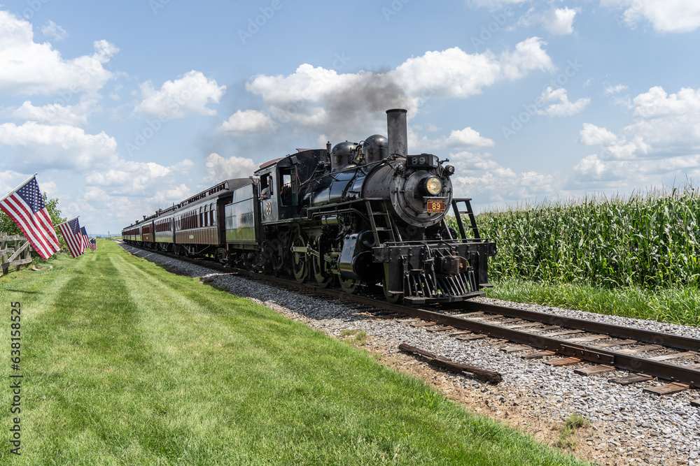 Strasburg, Pennsylvania – August 2023: Strasburg Steam Train rides along though corn fields in Lancaster County, Pennsylvania