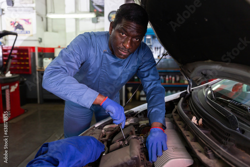 Professional man car mechanician repairing car in auto repair shop