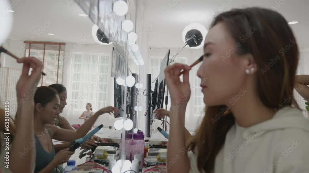 Cheerful diverse women applying makeup against mirror Cheerful diverse women applying makeup against mirror