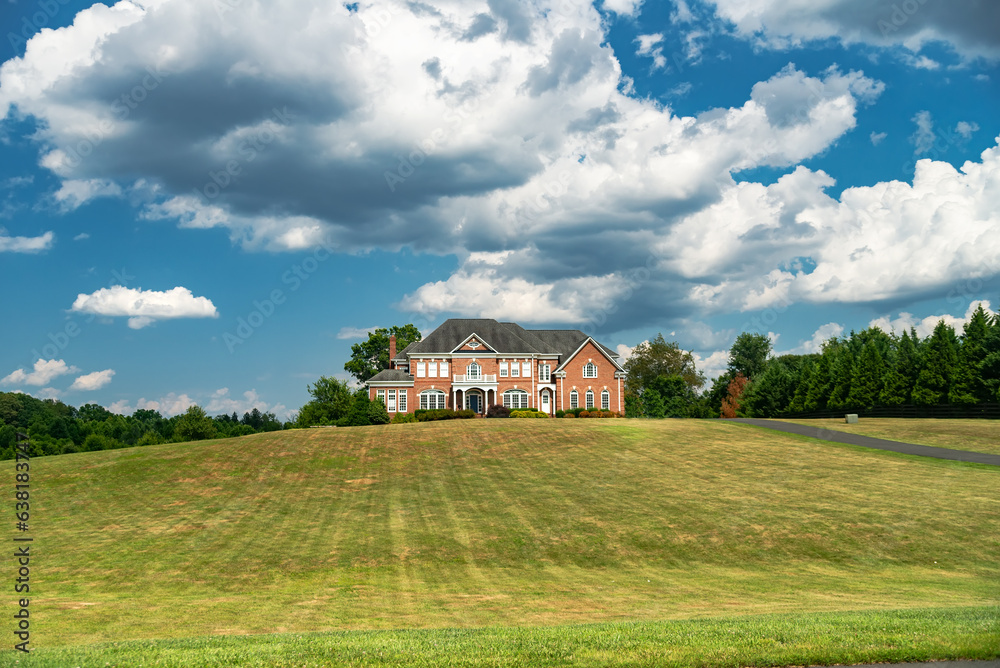 Country luxury brick house with large lawn under blue clouds. Country luxury brick house with large lawn under blue clouds.