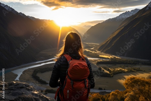 Female hiker with a backpack looking down the valley at sunset