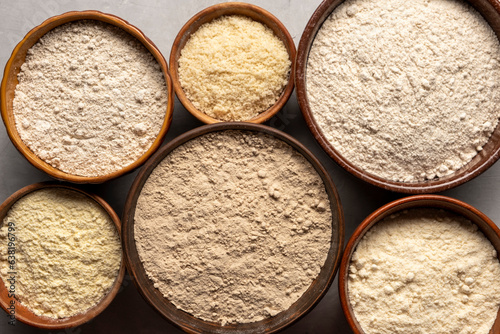 Set of organic flour in clay bowls on gray background photo