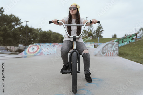 female rider sitting on a BMX in a bike park