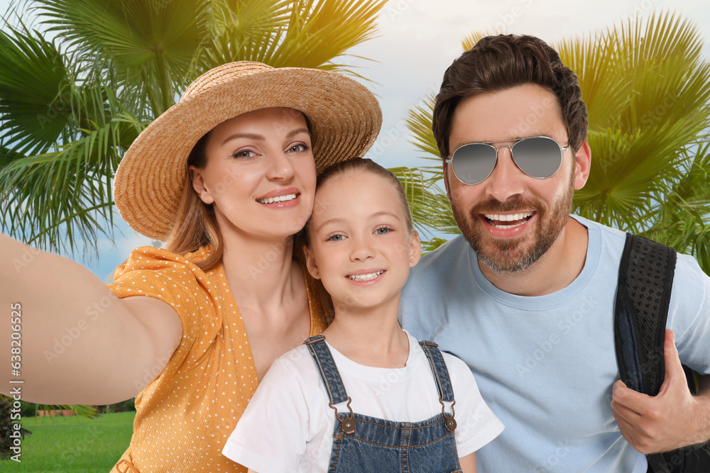 Happy family with child taking selfie near palm trees outdoors
