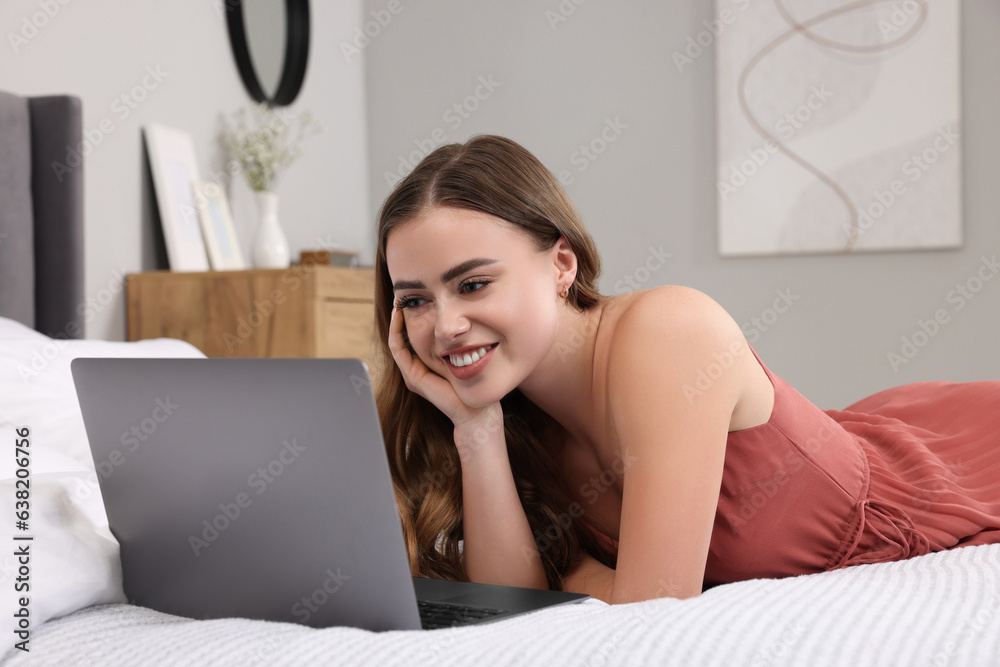 Happy woman with laptop on bed in bedroom Happy woman with laptop on bed in bedroom