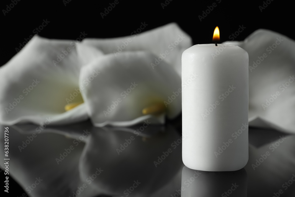 Burning candle and white calla lily flowers on black mirror surface in darkness, closeup with space for text. Funeral symbol Burning candle and white calla lily flowers on black mirror surface in darkness, closeup with space for text. Funeral symbol