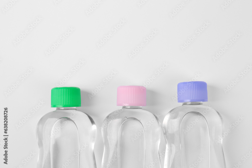 Transparent bottles with baby oil on white background, flat lay. Space for text Transparent bottles with baby oil on white background, flat lay. Space for text