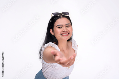A young asian woman extends her hand offering her help. A selfless lady warmly smiling being supportive. Isolated on a white background.