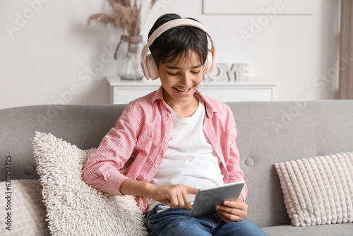 Little boy in headphones using tablet computer at home