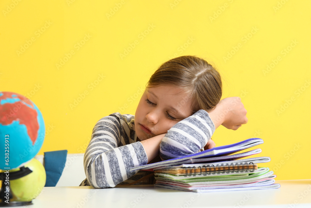 Little girl sleeping at table on yellow background Little girl sleeping at table on yellow background