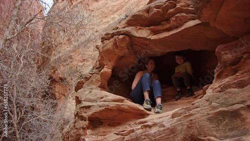 Woman and 5 year old son explore red rock cave in slot canyon, Escalante Utah
