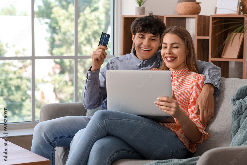 Young couple with laptop and credit card shopping online at home Young couple with laptop and credit card shopping online at home