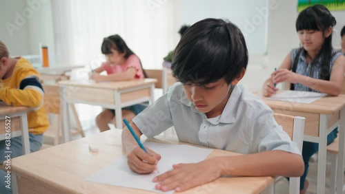 Diverse primary students doing an exam at elementary school. Teacher woman walking supervising examination of students at elementary school. Assessment and measure education.