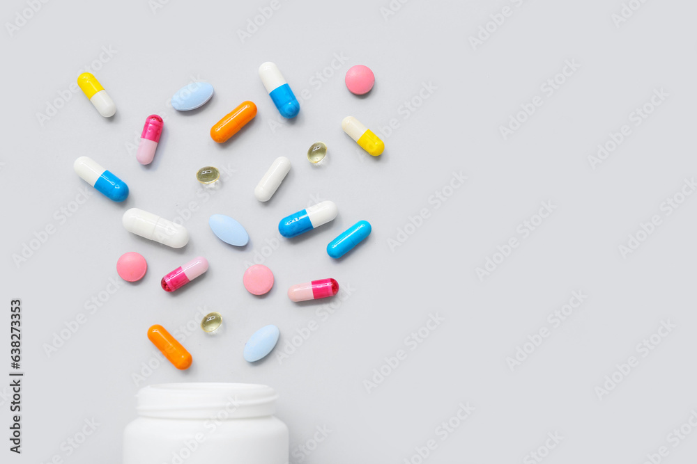 Composition with colorful pills and bottle on grey background