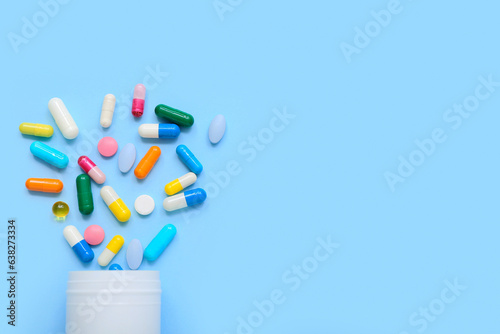 Overturned bottle with different pills on color background © Pixel-Shot