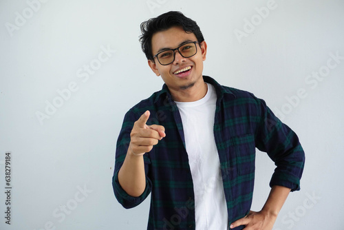 young asian man showing excited expression while pointing finger forward isolated on white background