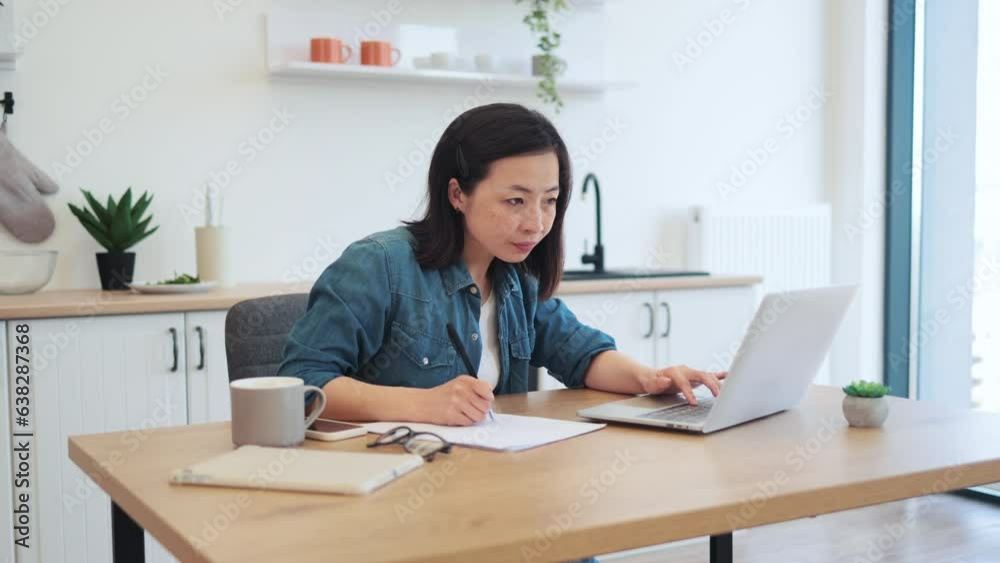 Adult writing down on paper while sitting behind laptop Adult writing down on paper while sitting behind laptop