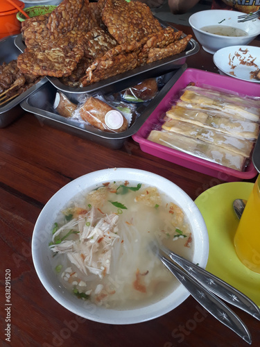 Soto Ayam (Indonesia's chicken soup with yellowish gravy). Assorted side dishes on the background. photo