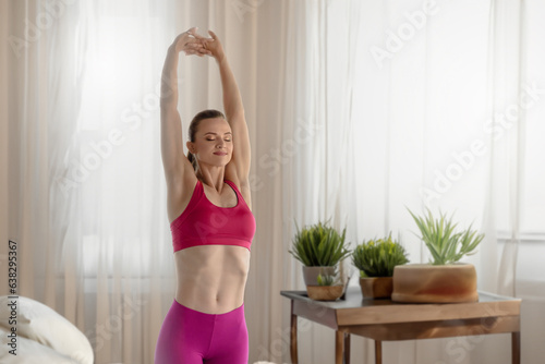 Beautiful young athletic girl in pink leggings and top training at home, Female exercising in comfortable home setting, stretching in athletic attire