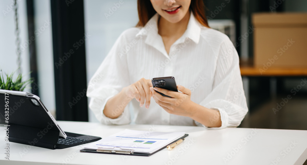 Businesswoman using mobile phone, tablet.Closeup on blurred background office.