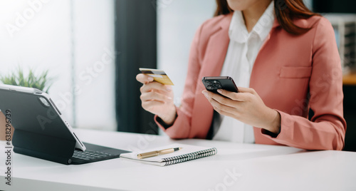 Woman using smart phone for mobile payments online shopping, omni channel, sitting on table, virtual icons graphics interface screen .