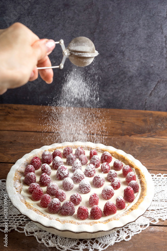 Round homemade raspberry cheesecake is decorated with powdered sugar