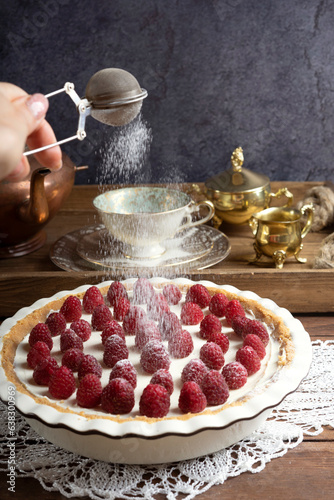 Round homemade raspberry cheesecake is decorated with powdered sugar