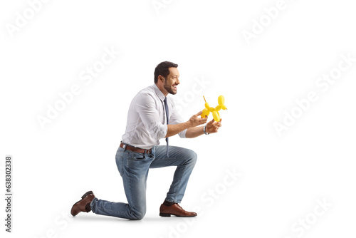 Fototapet Profile shot of a man kneeling and holding a dog made from a balloon