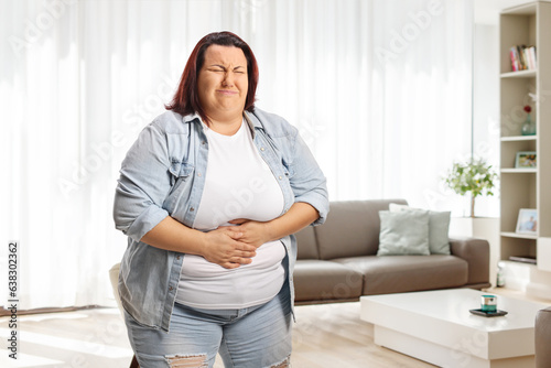 Foto Young overweight woman with abdominal pain at home