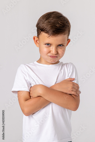 Negative human emotions, reactions and feelings. Isolated shot of moody displeased angry little boy crossing arms on his chest, pouting lips, having offended facial expression, being capricious
