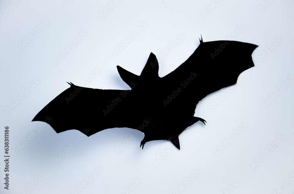 Fototapeta premium Silhouette of a bat cut out of black paper on a light background