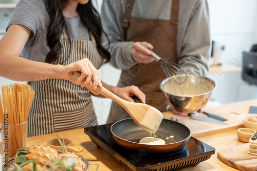 Cropped image of a lovely couple enjoying making pancakes in a minimalist kitchen together.