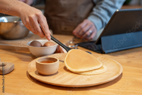 Close-up image of a woman making pancakes for her and her husband's breakfast in the kitchen.
