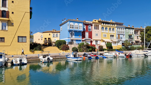 Walk through the streets and canals of the port of Saplaya on a sunny day. Moored yachts and boats at the bright facades of houses. Spain