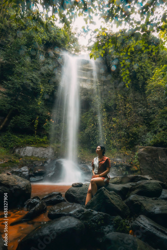 A young beautiful Asian girl explores a waterfall during her summer vacation in Laos  Asia