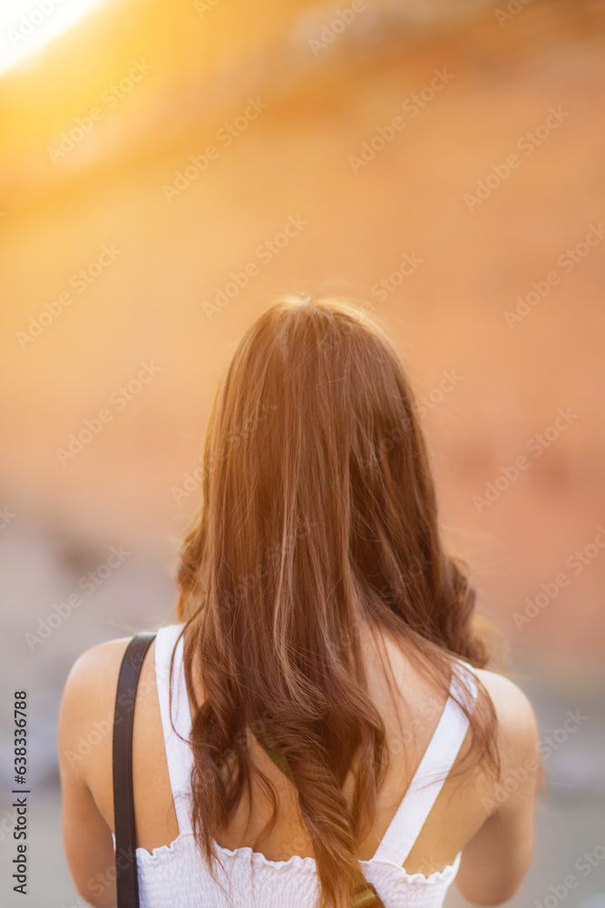 Asian tourists traveling and taking in sights of ancient city wall in Chiang Mai, Thailand, alone in summer. Back view of young female tourist taking walk taking in view of city wall and copy space