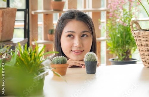 Portrait garden beautiful pretty young Asian girl woman wearing white blouse with long black hair and smile fresh with bright smile  look pot small tree leaf green plant in room shop Happy and relax