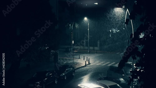 Summer rain in city downtown at night, drops of water shine in street lamp light.