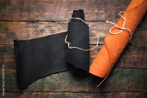 Leather rolls on the old wooden workbench background top view. Leather craft concept background.