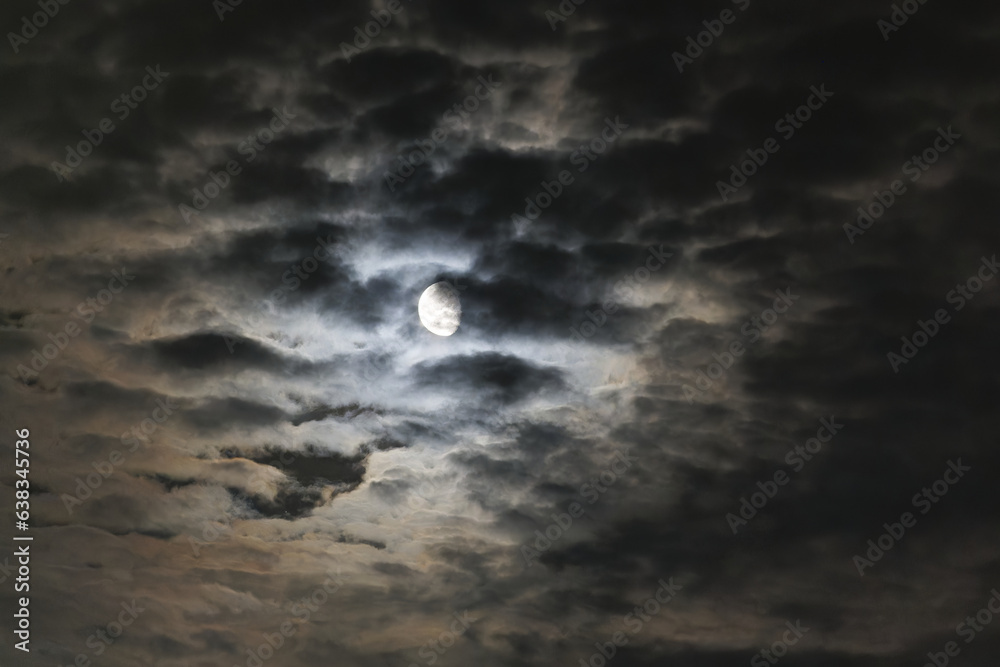 Looking up to bright moon up in the sky with clouds on a spring night. 