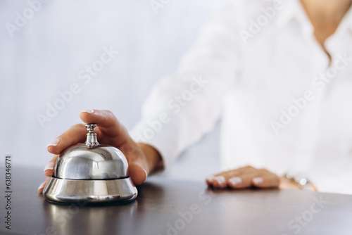 Business woman at the hotel lobby rings the counter bell, close up photo bell and hand