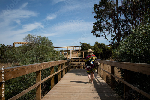 woman on holiday walking away on a wooden walkway. High quality photo.
