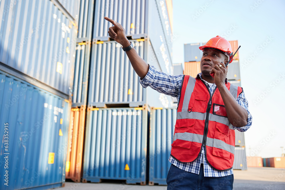 African factory worker or engineer using walkie talkie and talking about work in containers warehouse storage African factory worker or engineer using walkie talkie and talking about work in containers warehouse storage