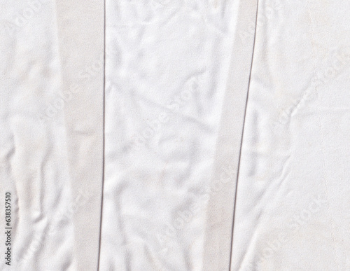 Folded and crumpled white cloth texture background. Rippled textile texture backdrop. Creased fabric graphic element.