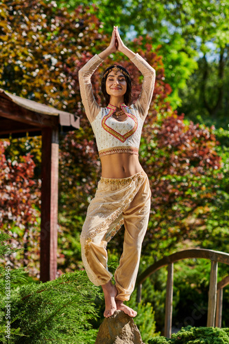 joyful indian woman in elegant ethnic wear standing with raised praying hands, summer happiness