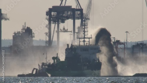 Ship Spraying Water from Water Cannon Near Container Terminal